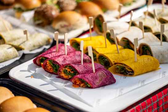 Roze en oranje wraps gevuld met vegetarische ingrediënten liggen gepresenteerd op een bord.