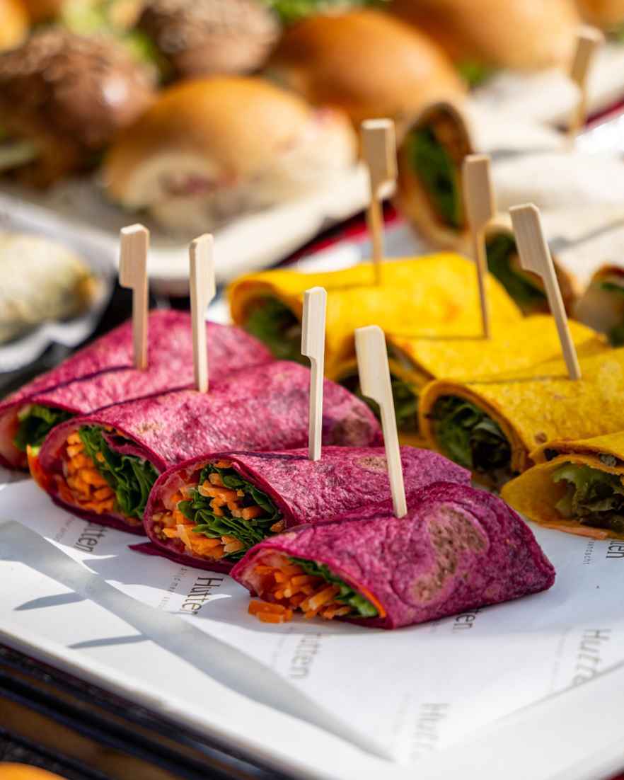 Roze en oranje wraps gevuld met vegetarische ingrediënten liggen gepresenteerd op een bord.