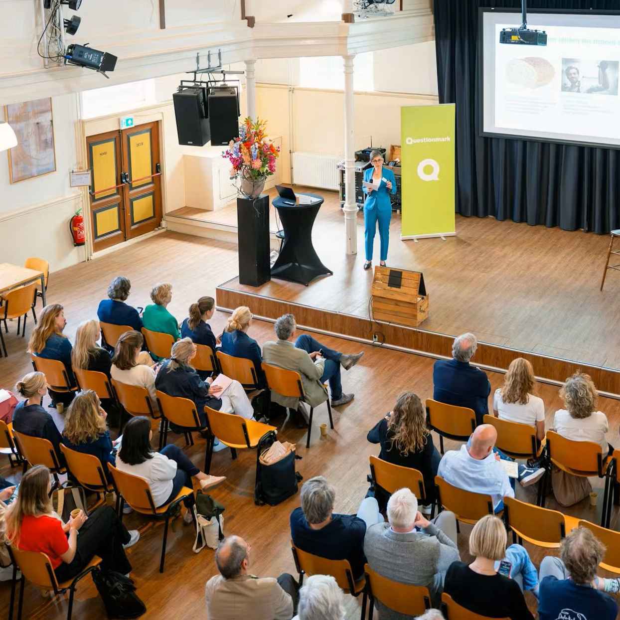 Spreker van Questionmark op een podium tegenover zittend publiek.
