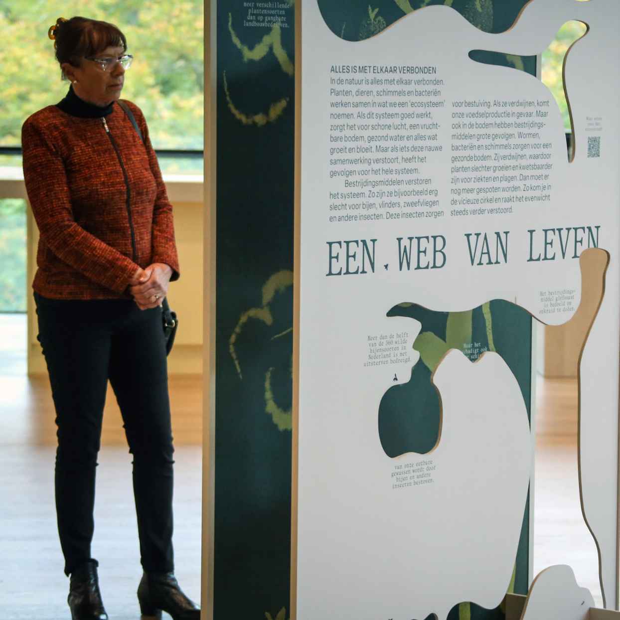 Vrouw kijkt naar paneel van tentoonstelling.