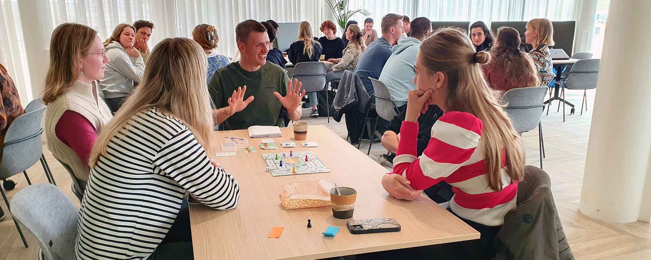 Tientallen jongeren zitten om de tafel en zijn in gesprek over het programma Oogst van Overmorgen. Ze spelen ondertussen de Serious Game: Ganzenbordspel Tussen stad en stal.